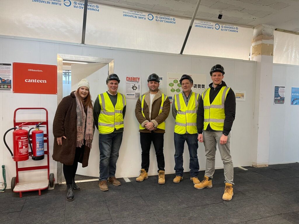 A woman in a brown coat stand in line with four men in hi-vis jackets and helmets - the OD Interiors team.